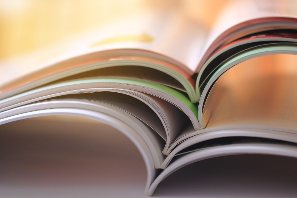 you can see several magazines lying on top of each other in front of a light background